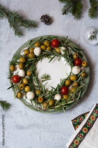 Christmas wreath on a mozzarella plate of cherry tomatoes and olives, decoration for the Christmas table . photo