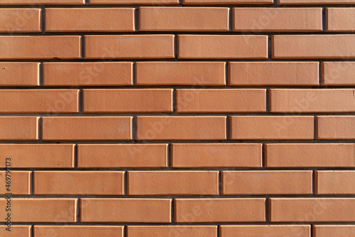 Orange brick wall in natural sunlight, even rows of bricks