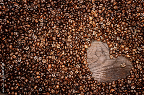 Coffee beans arranged as a heart shape on old wooden background
