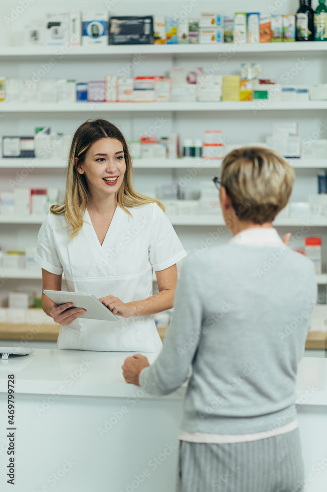 Obraz premium Male pharmacist selling medications at drugstore to a senior woman customer