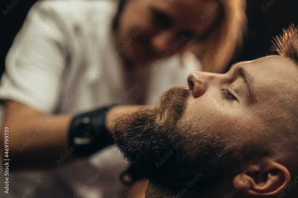 Young bearded man getting beard haircut by hairdresser Young bearded man getting beard haircut by hairdresser