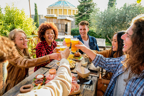 Group of multiethnic happy friends living healthy lifestyle and relaxing while drinking beer at outdoor pub restaurant - Young people enjoying drinks during happy hour at bar
