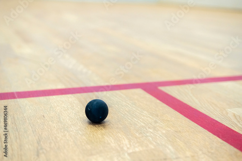 the squash ball lies on the wooden floor between the lines dividing the squash zones