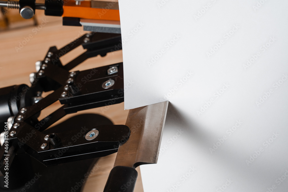 Process of cutting paper with a sharp knife near professional knife sharpener and a set of sharpening stones. Process of cutting paper with a sharp knife near professional knife sharpener and a set of sharpening stones.