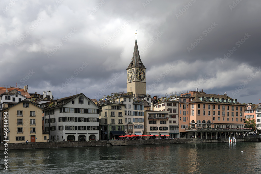 View of the promenade of Limmat river and ancient St. Peter Church. Zuerich, Switzerland, Europe.