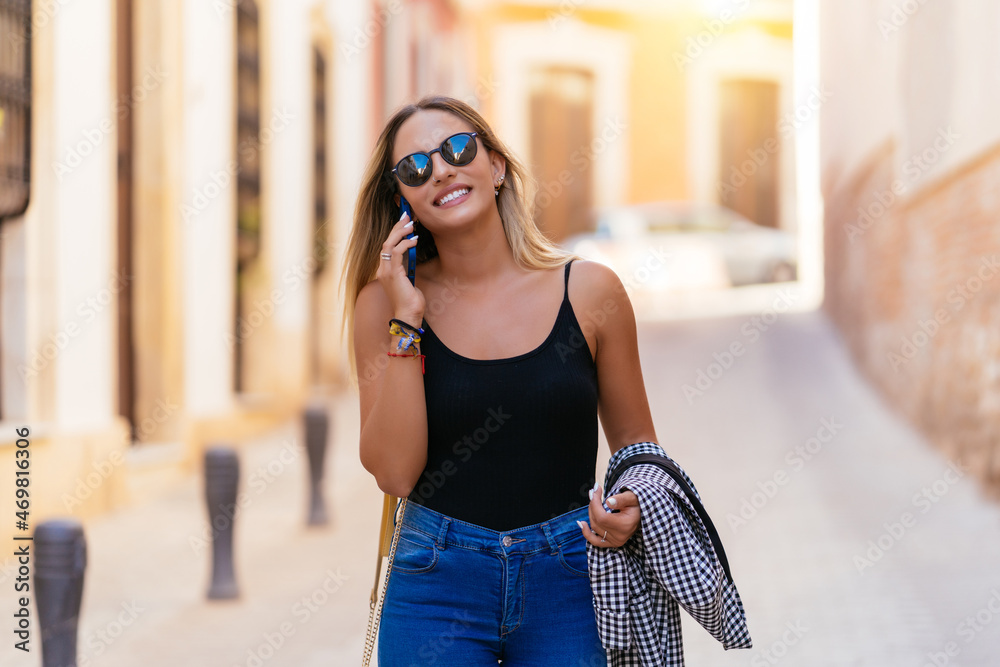 Fototapeta premium Stylish woman talking on smartphone in city