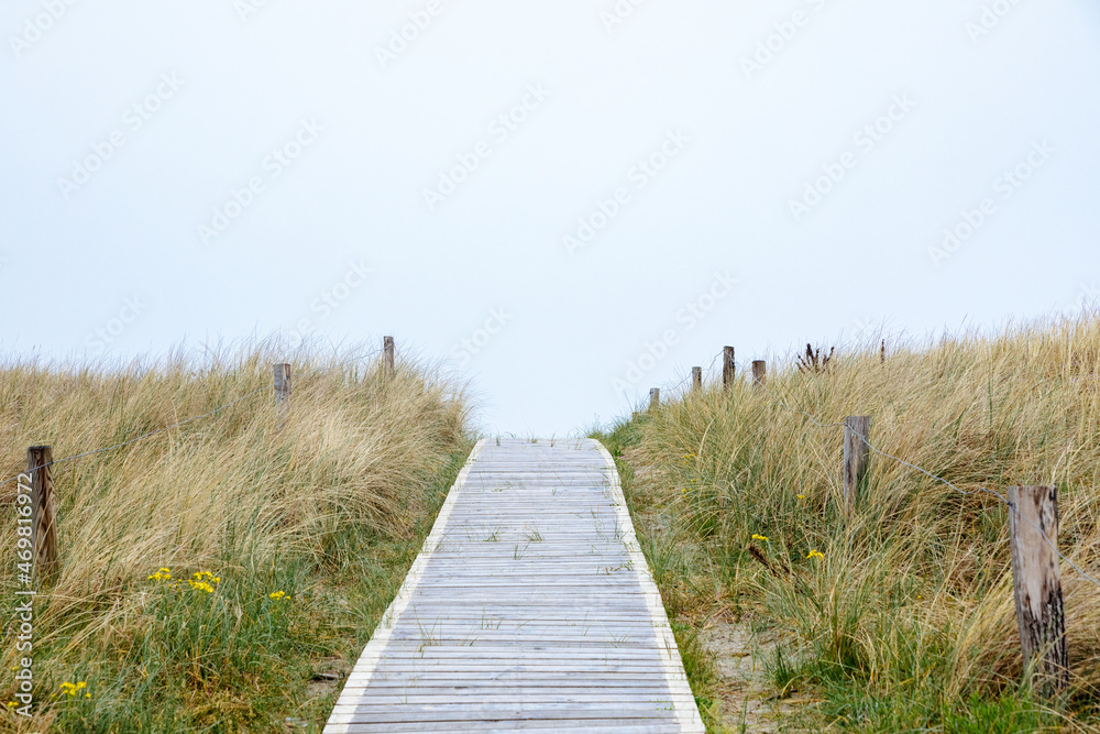 Path made of wooden slats between the dunes on the North Sea. Beach on the North Sea. Vacation in Germany. Beach wedding	