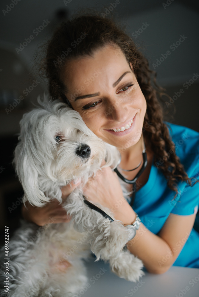 Veterinarian smiling while cuddling with a dog. Veterinarian smiling while cuddling with a dog.