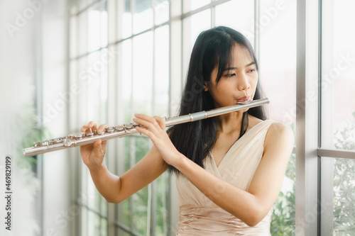 A female flutist performs on her instrument. A young and elegant Asian woman plays the flute photo