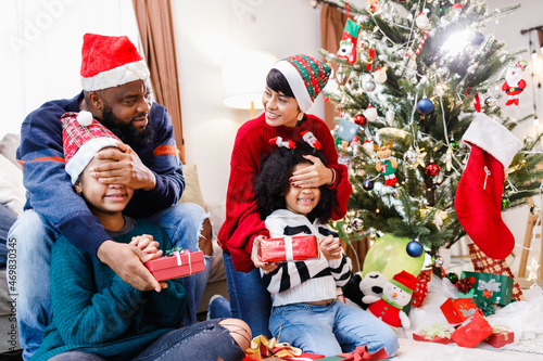 African American family surprising with a gift on Christmas day. Merry Christmas. Happy family.