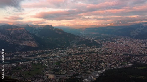 Aerial time lapse of Grenoble city surrounded by alps mountains during cloudy sunset. Famous tourist destination in france mountain