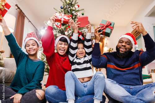 African American family in Christmas theme. Happy African American family of four bonding sitting on the floor together with Christmas decorations in the living room.
