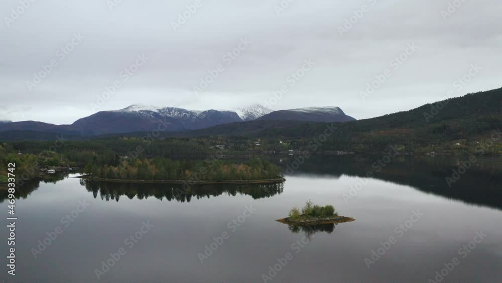 Calm Lake With Small Islands And Mountain Snowy View in The Background, Norway. - Aerial, pull in Calm Lake With Small Islands And Mountain Snowy View in The Background, Norway. - Aerial, pull in