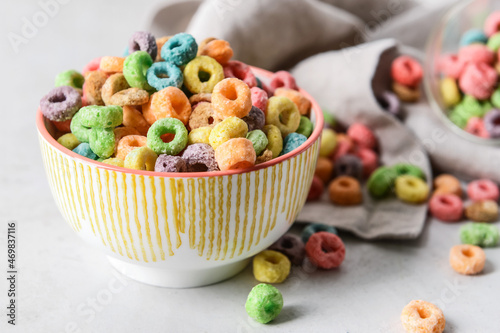 Bowl with crunchy corn flakes rings on light background