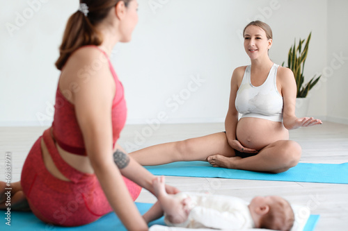 Young pregnant woman with trainer and little baby at gym
