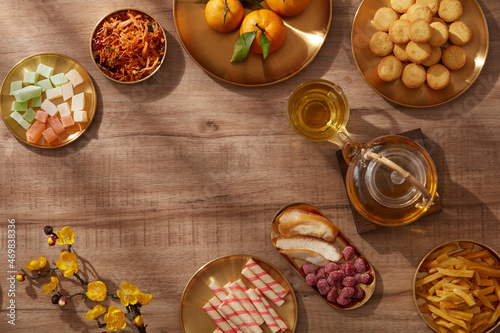 Happy lunar new year with mandarin orange teapot in golden dish candy jam , fried potato flower red pocket biscuit , wooden background photography Tet holiday content , chinese new year