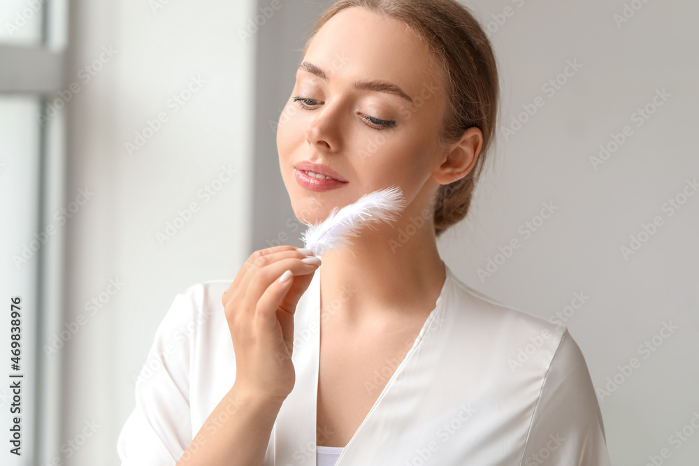 Beautiful young woman with soft feather at home Beautiful young woman with soft feather at home