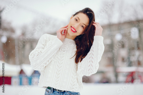 Young girl in a white sweater standing in a winter park