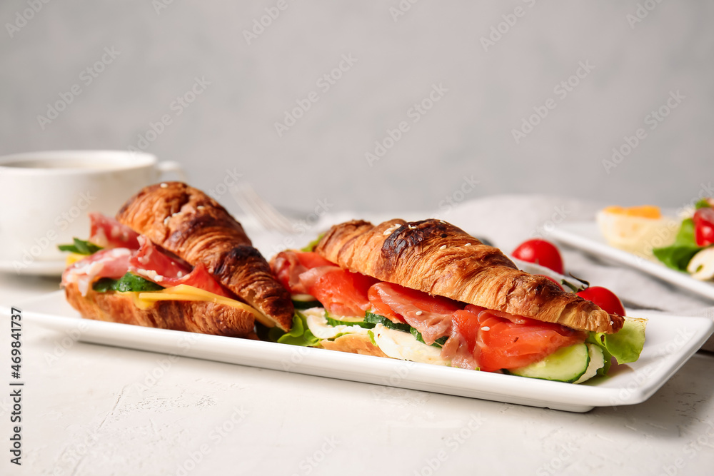 Plate with delicious croissant sandwiches on white background Plate with delicious croissant sandwiches on white background