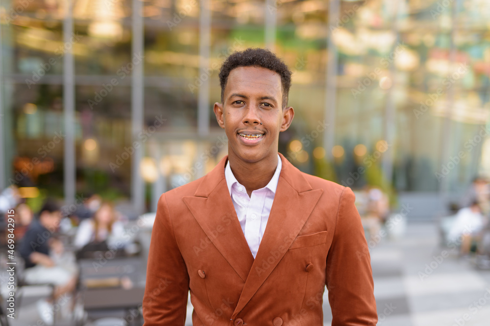 Portrait of handsome black African businessman smiling outdoors in city Portrait of handsome black African businessman smiling outdoors in city