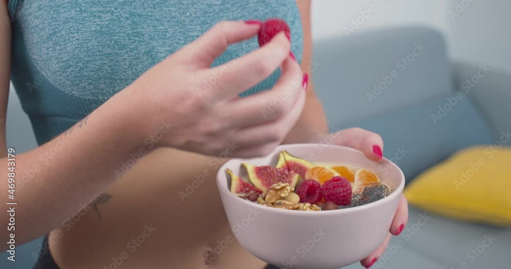 Athletic young lady eating a healthy meal of fruit, nuts and seeds, close up. Athletic young lady eating a healthy meal of fruit, nuts and seeds, close up.
