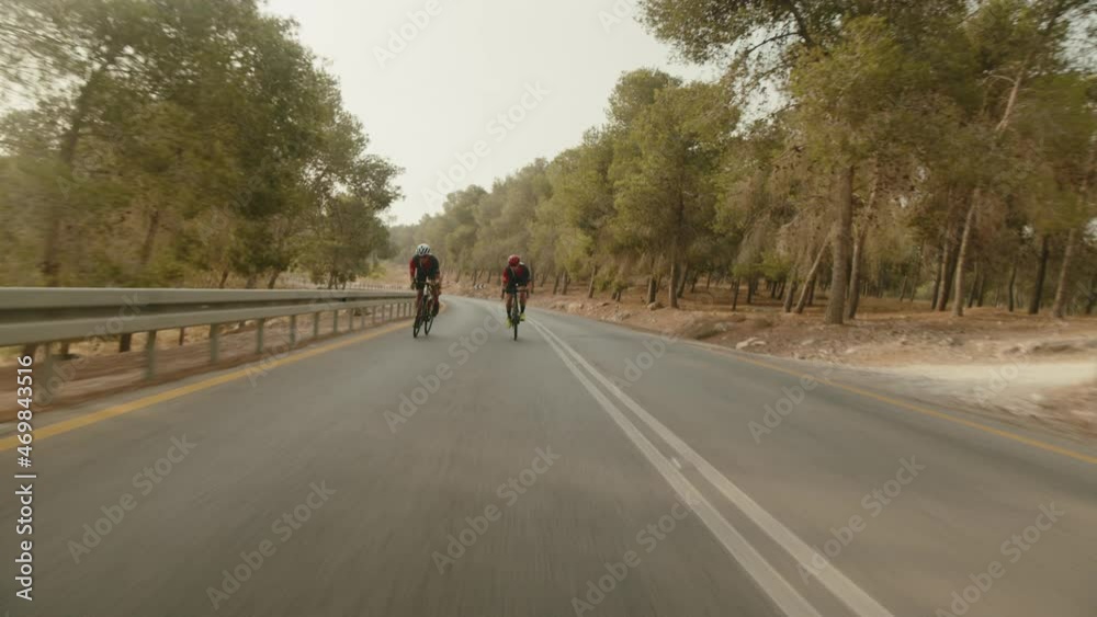 slow motion wide shot of two road cycelist professionals riding in the desert's empty road slow motion wide shot of two road cycelist professionals riding in the desert's empty road