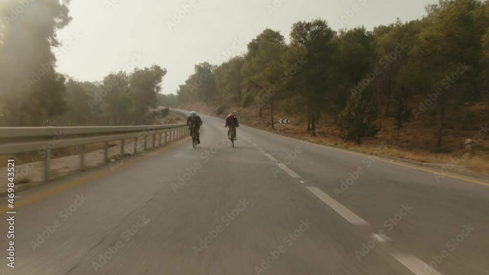 two road cycelist professionals riding in the desert's empty road trying to gain more speed two road cycelist professionals riding in the desert's empty road trying to gain more speed