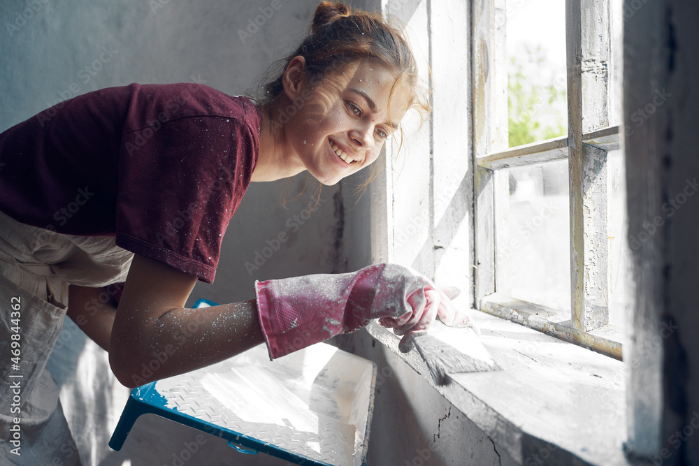 woman with brush paints window sill at home near window interior renovation woman with brush paints window sill at home near window interior renovation
