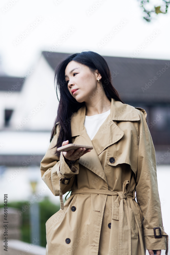 Stylish young asian woman dressed in casual wear looking away when posting photos in social media and thinking about interesting content text. Lifestyle blogger checking blog comments outdoor at Stylish young asian woman dressed in casual wear looking away when posting photos in social media and thinking about interesting content text. Lifestyle blogger checking blog comments outdoor at