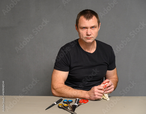 Adult serious man wipes blood from hand on gray background photo