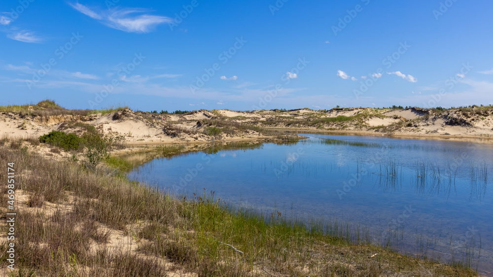 Blue water pond in the middle of sand dunes covered with dune grass near Ludington , Michigan