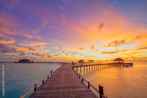 Sunset on Maldives island  luxury water villas resort hotel and wooden pier. Colorful sky and clouds and beach background for summer vacation holiday  traveling destination. Paradise sunset landscape