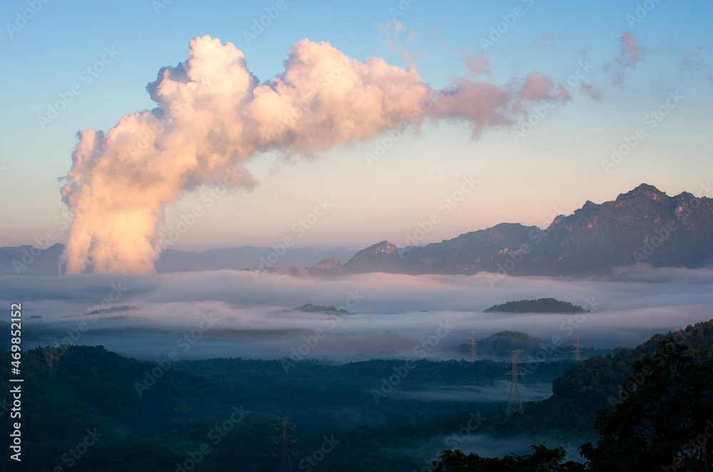 Beautiful sea of fog in the mountains, high voltage pole and steam from the coal power plant in the morning sunrise . Mae moh, Lampang, Thailand. Energy and environment concept .

