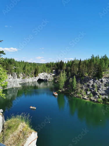 Fototapeta Naklejka Na Ścianę i Meble -  View from the observation deck of the turquoise water of the Marble Canyon in the Ruskeala Mountain Park with the reflection of the sky and trees on a sunny summer day.