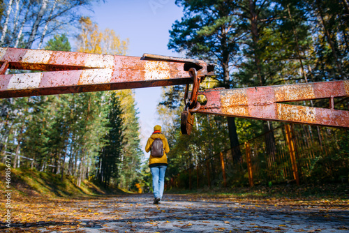 Rusty iron gate, closed road to the park. Woman violated the border of protected area. Focus on padlock.