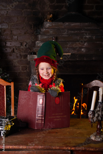a little girl in an elf costume for the New Year holiday depicts laughter and joy holding a book in her hands for Christmas