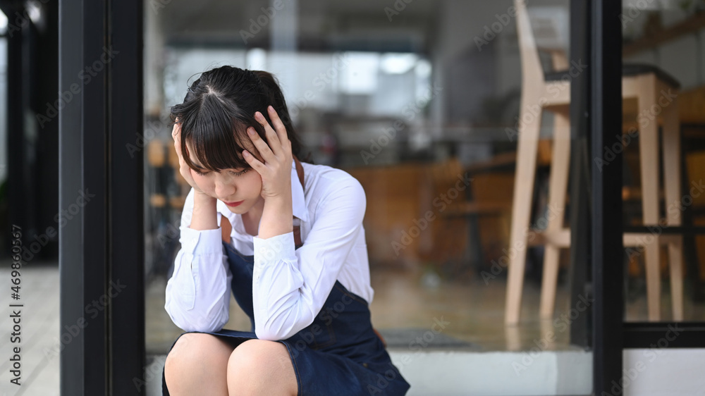 Young woman coffee shop business owner stressed because of economic conditions.