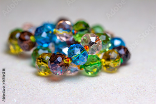 Full frame macro abstract texture background of a string of defocused multicolor glass beads on white background