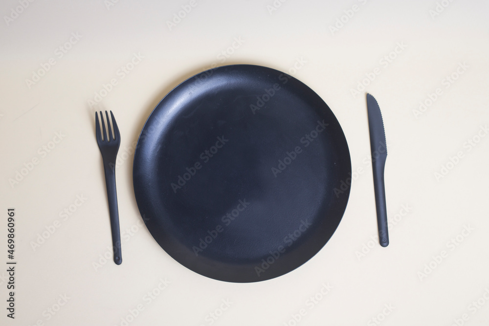 black plastic knife and fork and black plate isolated on light background flat lay black plastic knife and fork and black plate isolated on light background flat lay