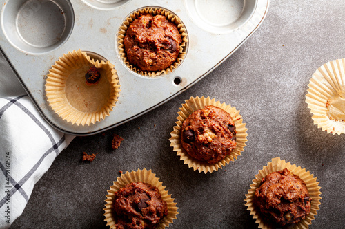Foto Fruit and nut chocolate cupcakes in liners and nonstick tray served fresh out of oven for breakfast on stone countertop