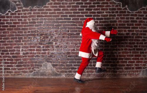 Santa Claus for the New Year and Christmas on the background of a brick wall runs away