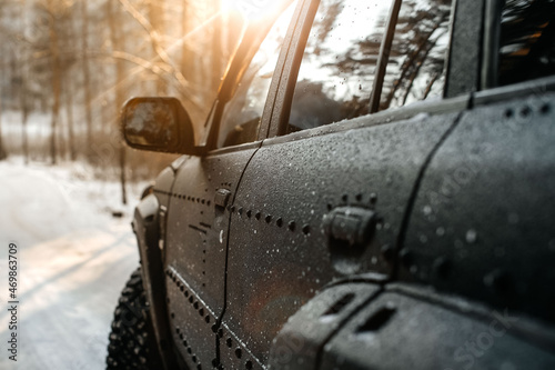 Black SUV, rear view of a snowy winter road in the forest in the early morning. Winter conditions.