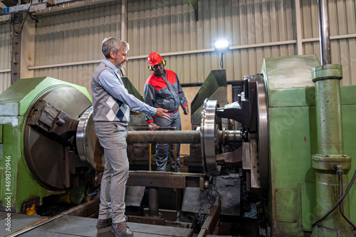 Multiracial Industrial Co-Workers  Standing And Talking Next To Lathe Machine In A Train Factory - Train Wheel Manufacturing © RGtimeline