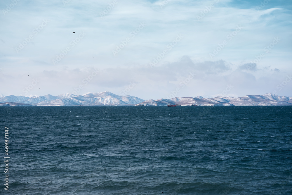 Winter landscape of the Avacha bay. Snowy mountains and stormy ocean.