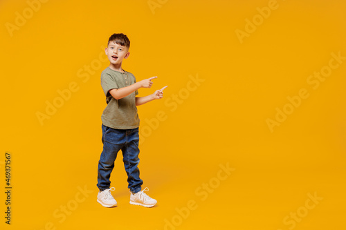 Canvas Print Full body little small smiling happy boy 6-7 years old wearing green t-shirt point index finger aside on workspace area isolated on plain yellow background Mother's Day love family lifestyle concept