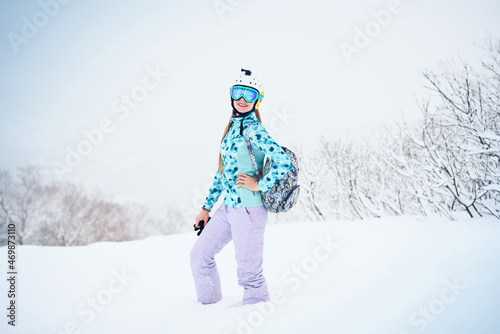 Portrait of cheerful skier girl in blue sweater and yellow helmet in a snowy weather
