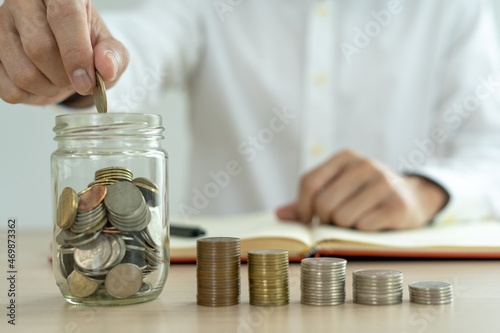 Businessman holding a coin in a piggy bank. Money saving , financial accounting, income and investment concept.