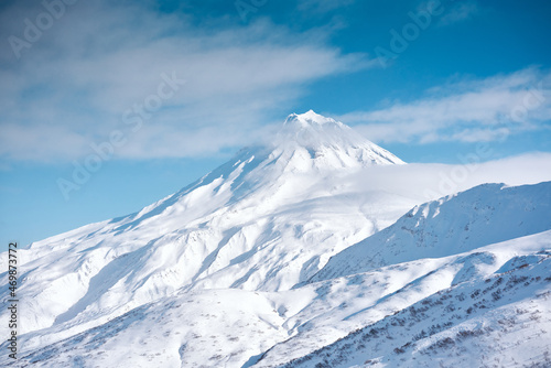 Winter landscape. Vilyuchinsky volcano covered with snow against blue sky. Kamchatka peninsula, Russia