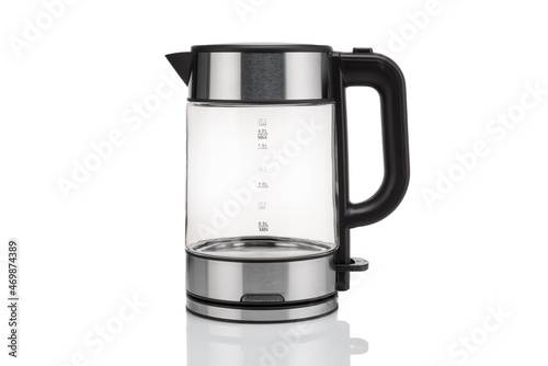 Glass, electric, modern transparent kettle on a white background. Close-up. With a reflex on the table