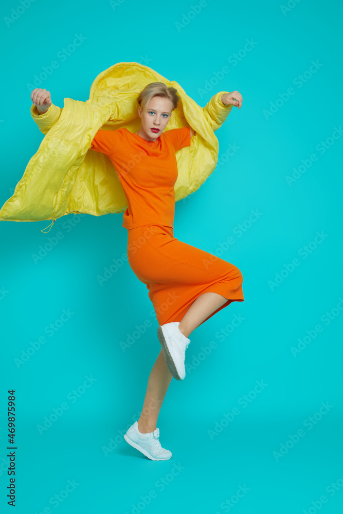 Fashion model in yellow down jacket, orange skirt and sweater. Fashion model in yellow down jacket, orange skirt and sweater.